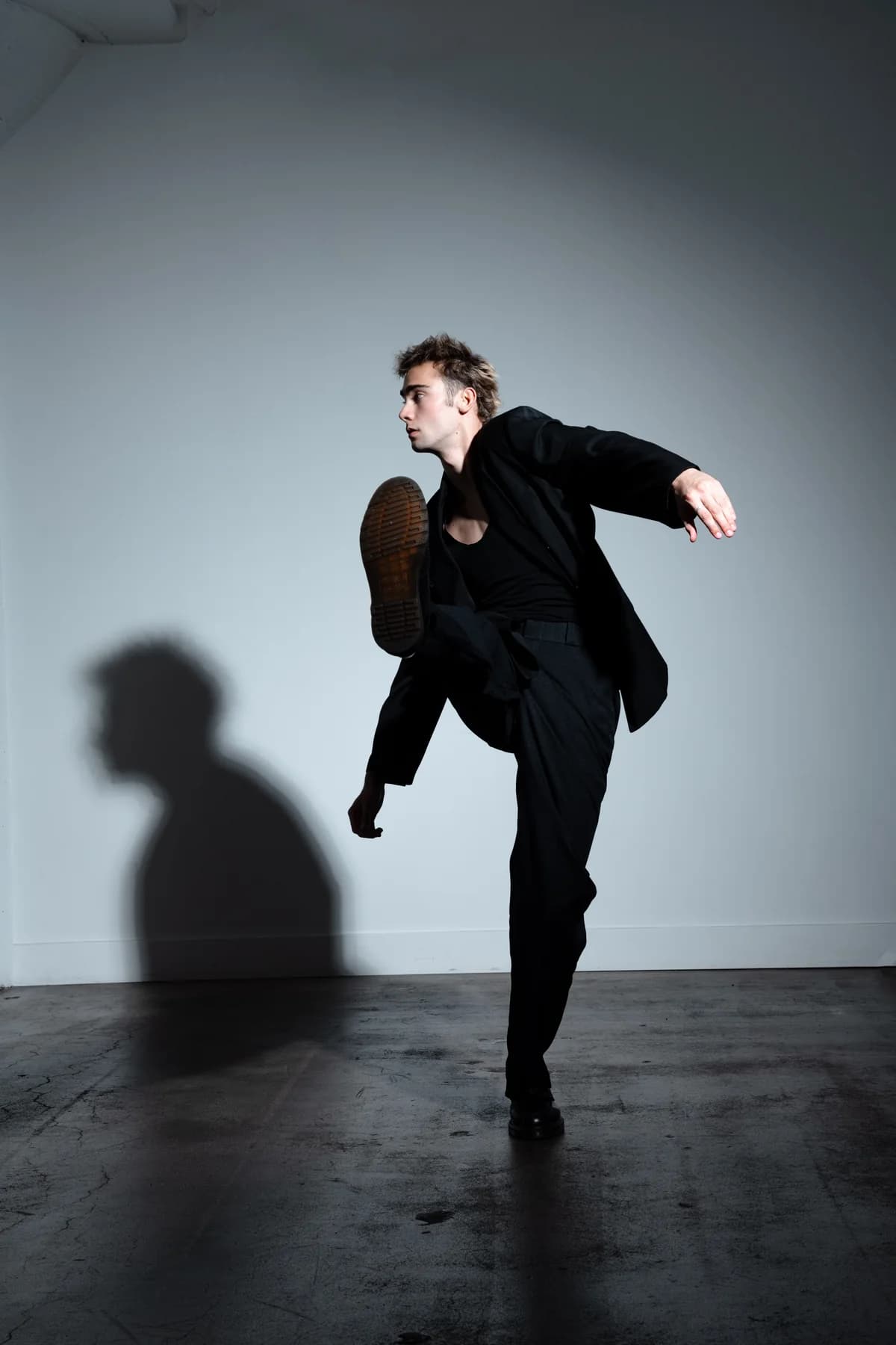 Jeffrey Bull balancing in a high kick while wearing a black suit